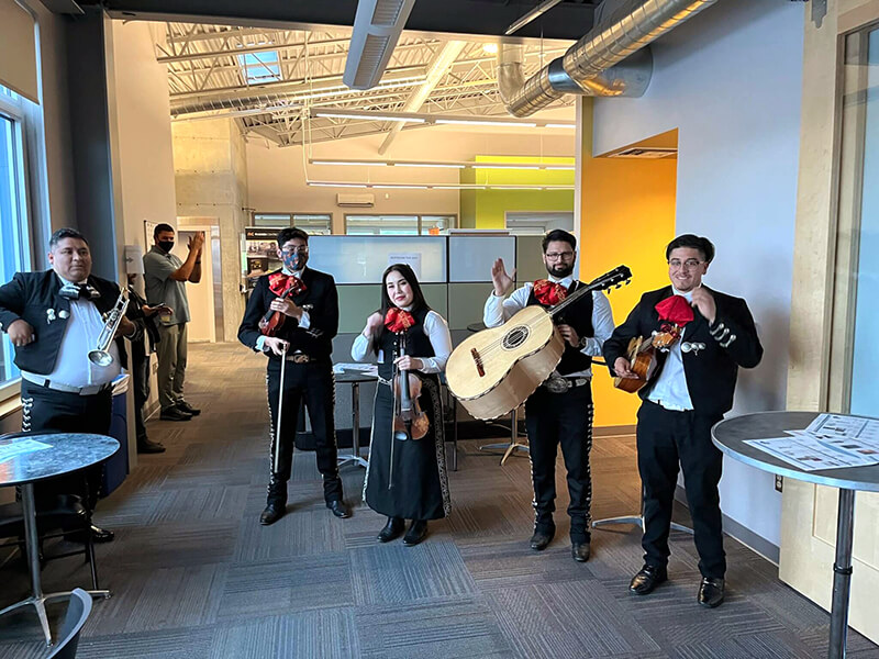 5 members of a mariachi band in an office